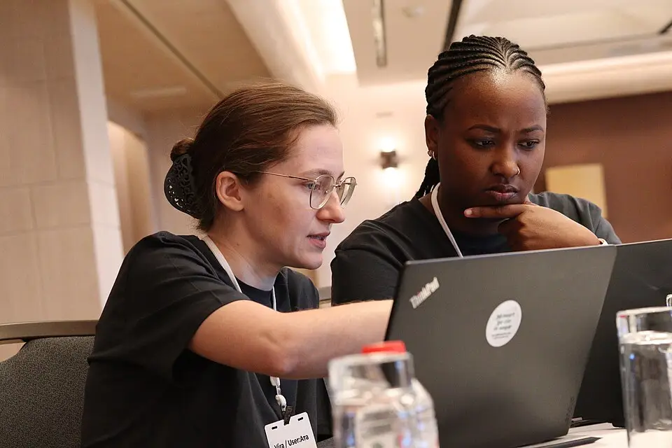 Two people building together on laptops at night