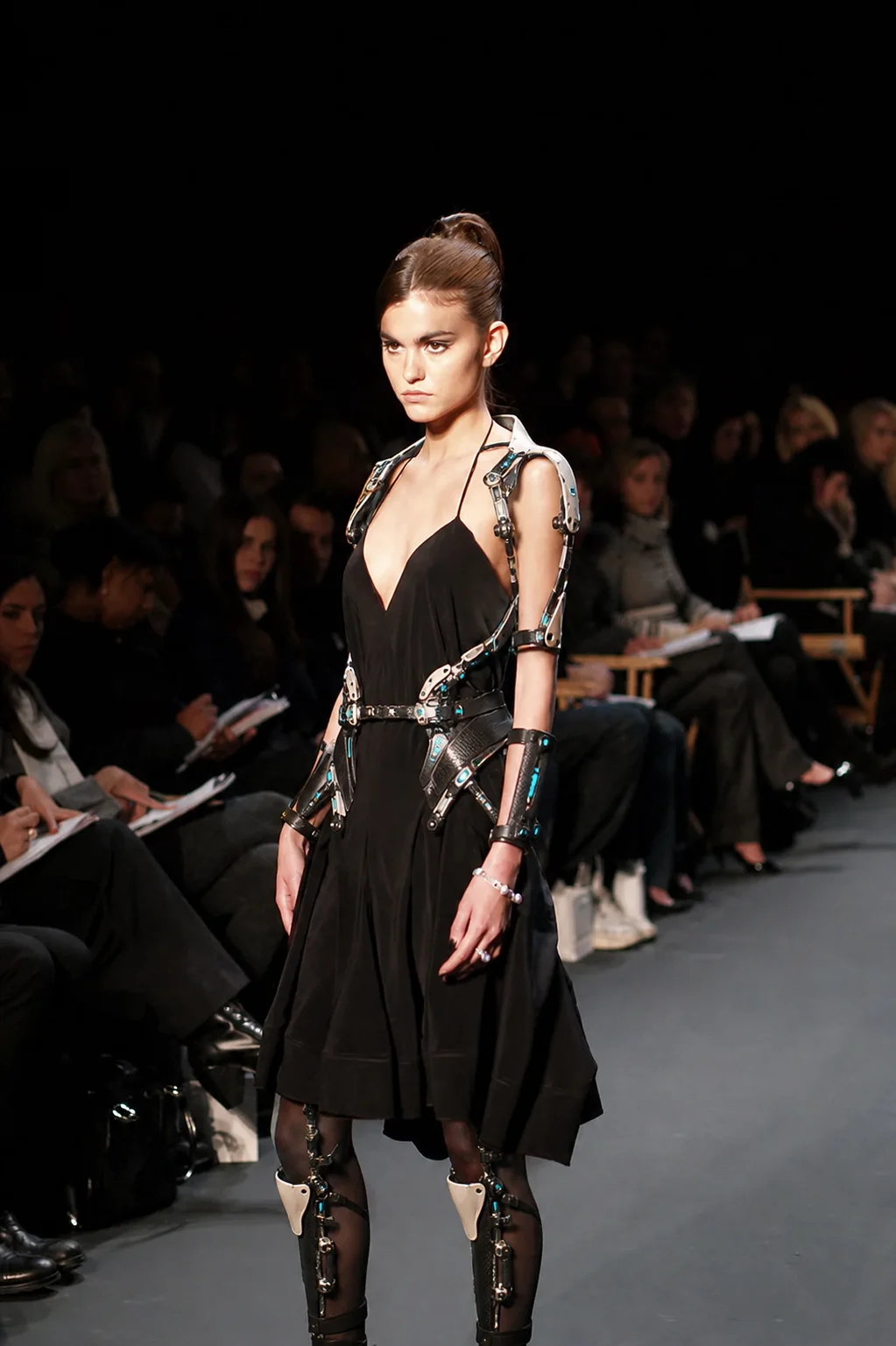 Model presenting a lightweight articulated exoskeleton integrated into a black runway dress